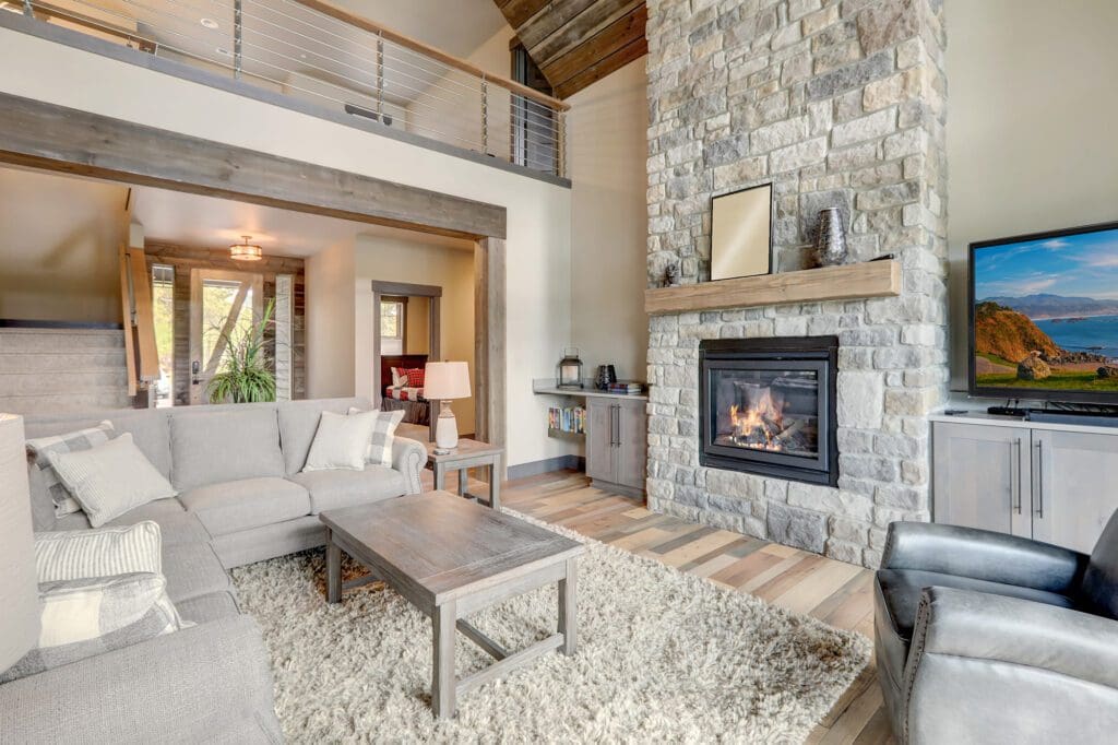 A living room with a large natural stone fireplace.
