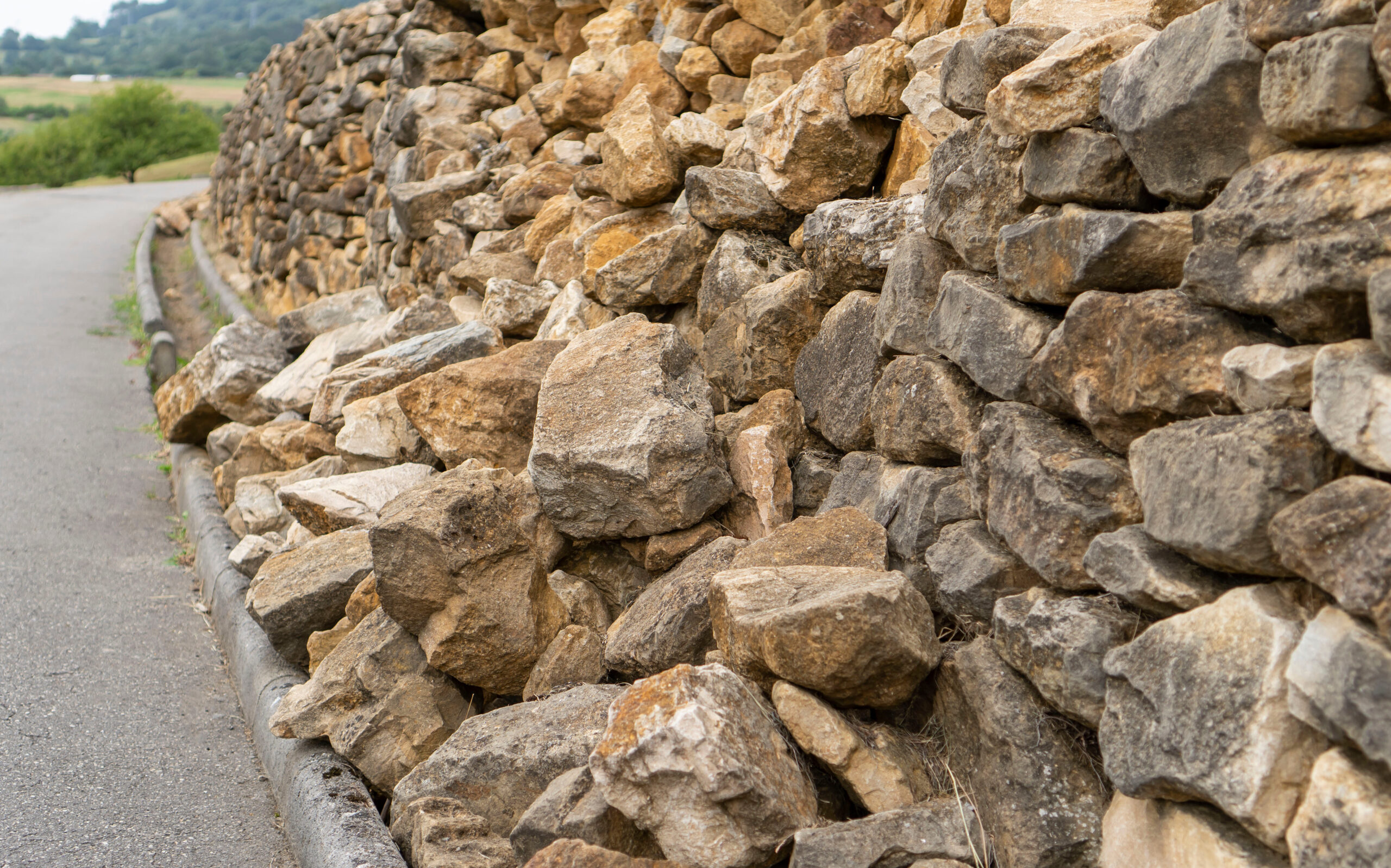 A portion of a stone retaining wall falls apart after heavy rains.