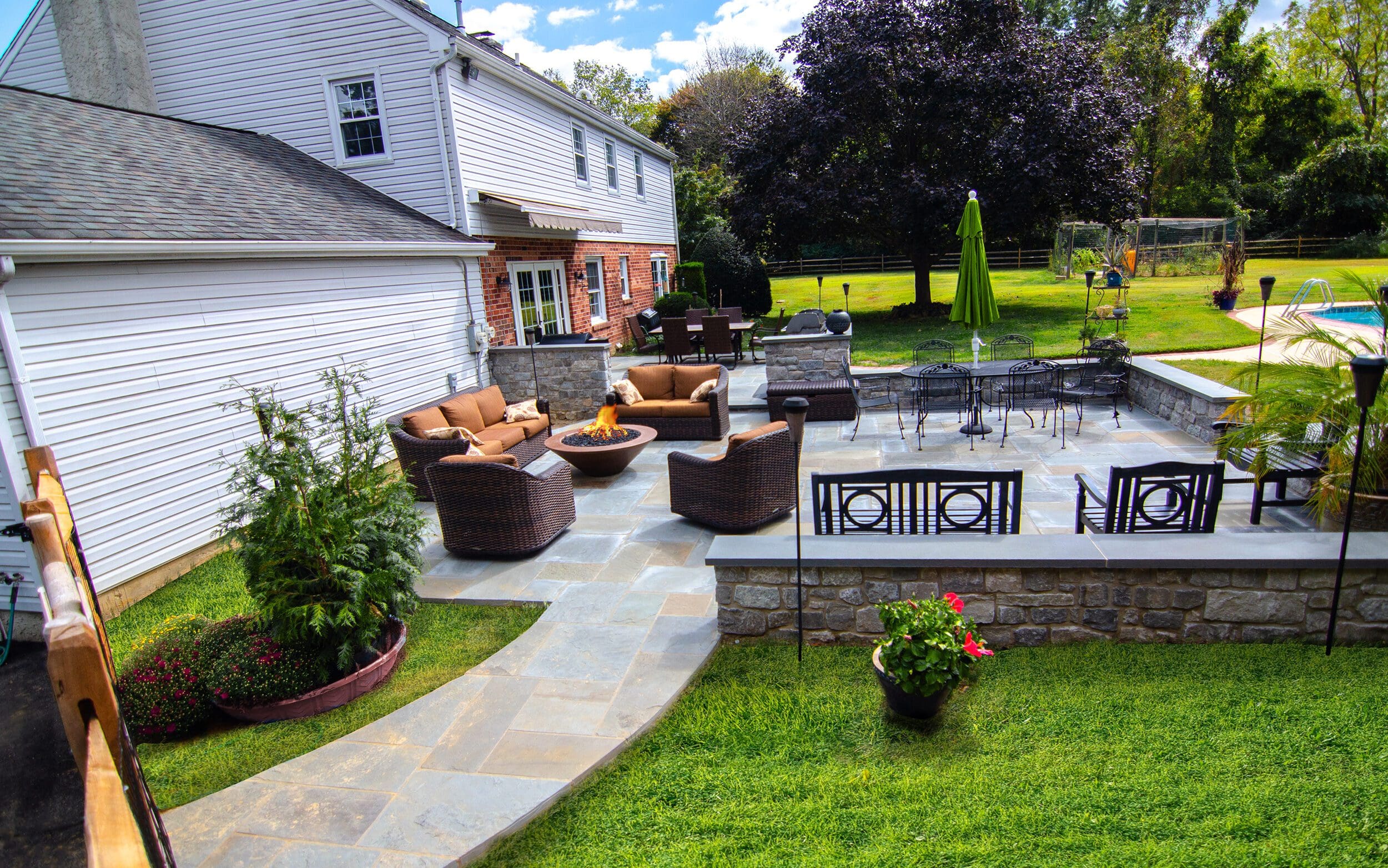 A beautiful stone walkway leads to a stone patio designed by Dutchies Stoneworks.