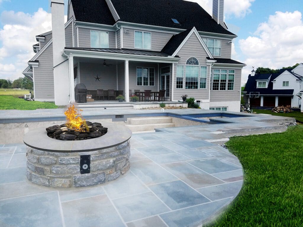 A gas-powered stone fireplace on a stone patio by a pool.