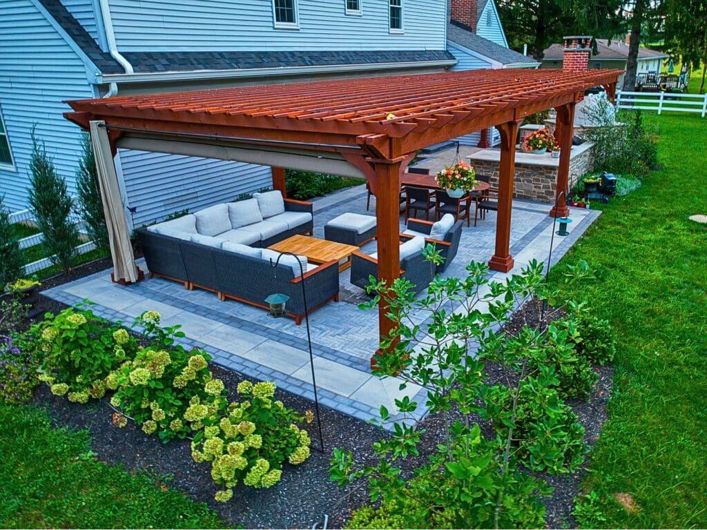 Explore this custom outdoor kitchen and pergola transformation featuring an integrated masonry pizza oven, Blaze appliances, and a Techo-Bloc Westmount paver patio