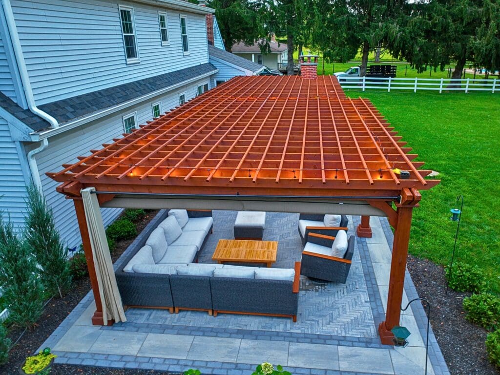 Explore this custom outdoor kitchen and pergola transformation featuring an integrated masonry pizza oven, Blaze appliances, and a Techo-Bloc Westmount paver patio
