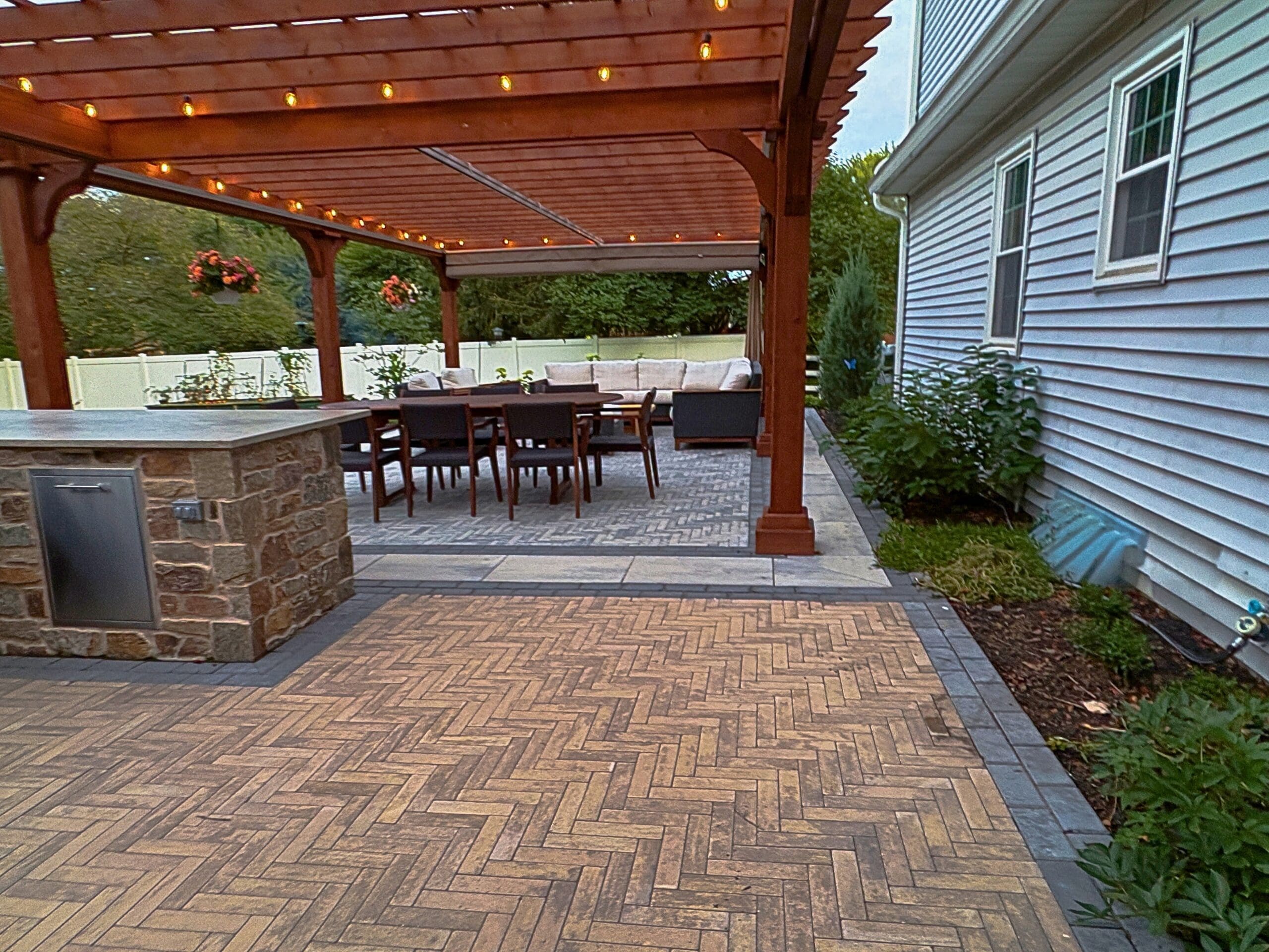 Explore this custom outdoor kitchen and pergola transformation featuring an integrated masonry pizza oven, Blaze appliances, and a Techo-Bloc Westmount paver patio