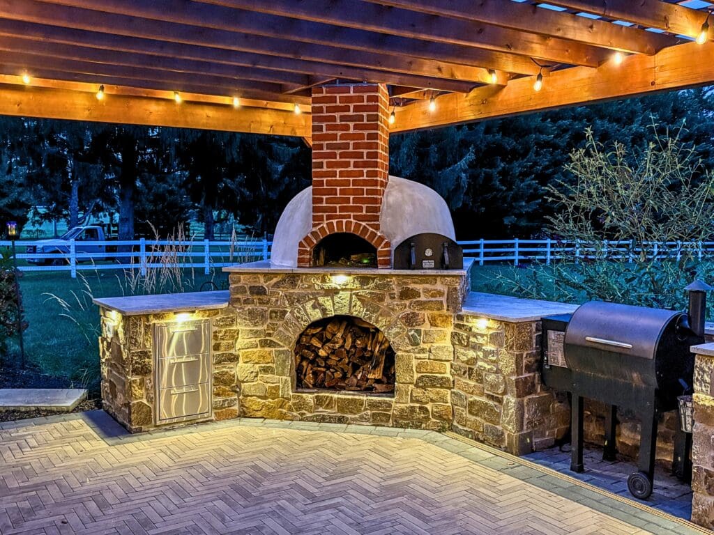 Explore this custom outdoor kitchen and pergola transformation featuring an integrated masonry pizza oven, Blaze appliances, and a Techo-Bloc Westmount paver patio