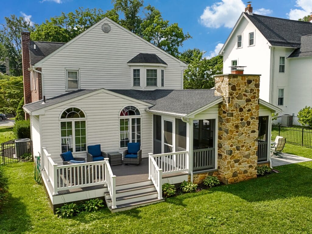 Explore this custom outdoor living transformation featuring an AZEK screened porch, Chester County natural stone fireplace, flagstone patio, and TimberTech composite deck.