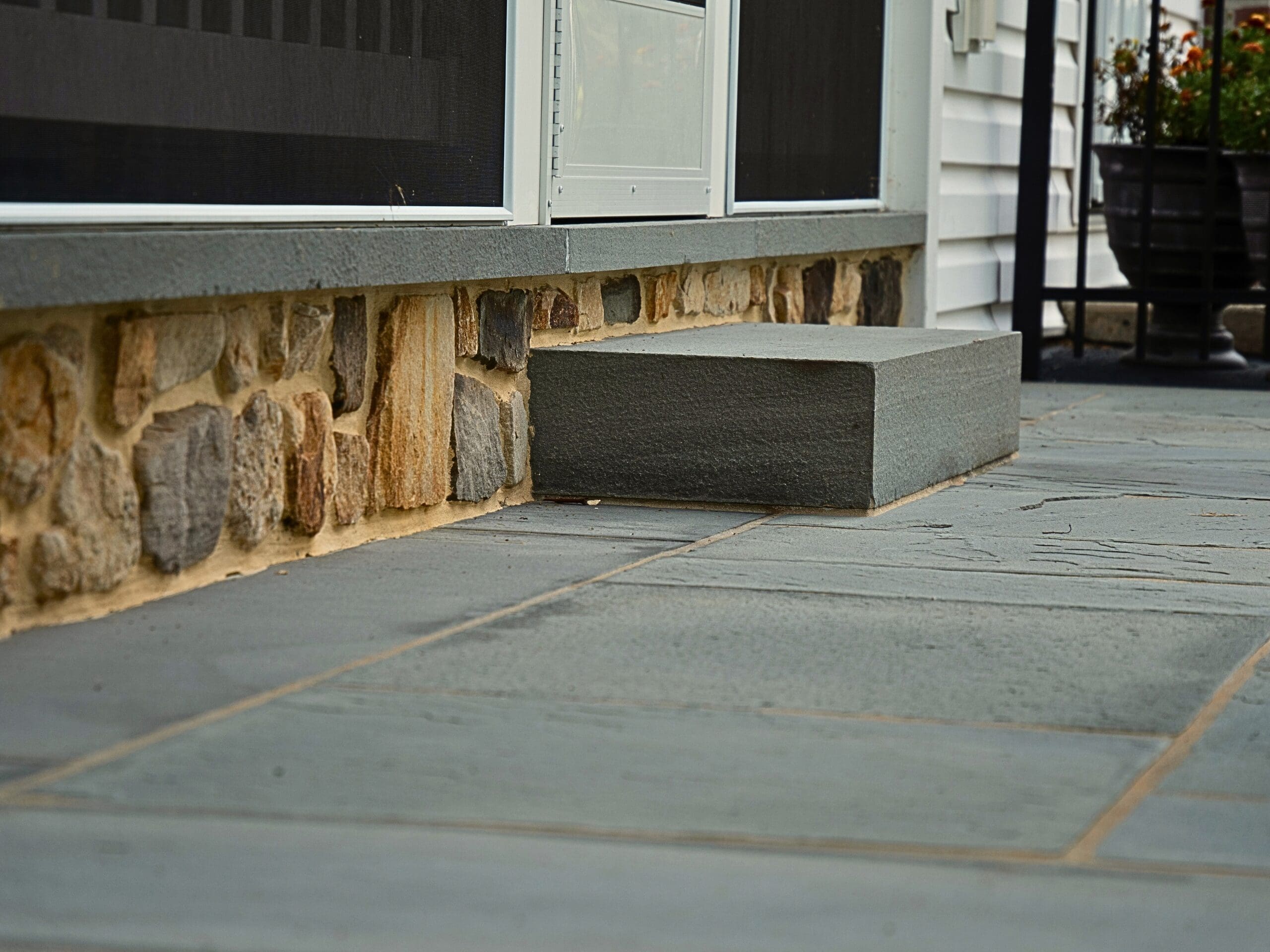 Explore this custom outdoor living transformation featuring an AZEK screened porch, Chester County natural stone fireplace, flagstone patio, and TimberTech composite deck.