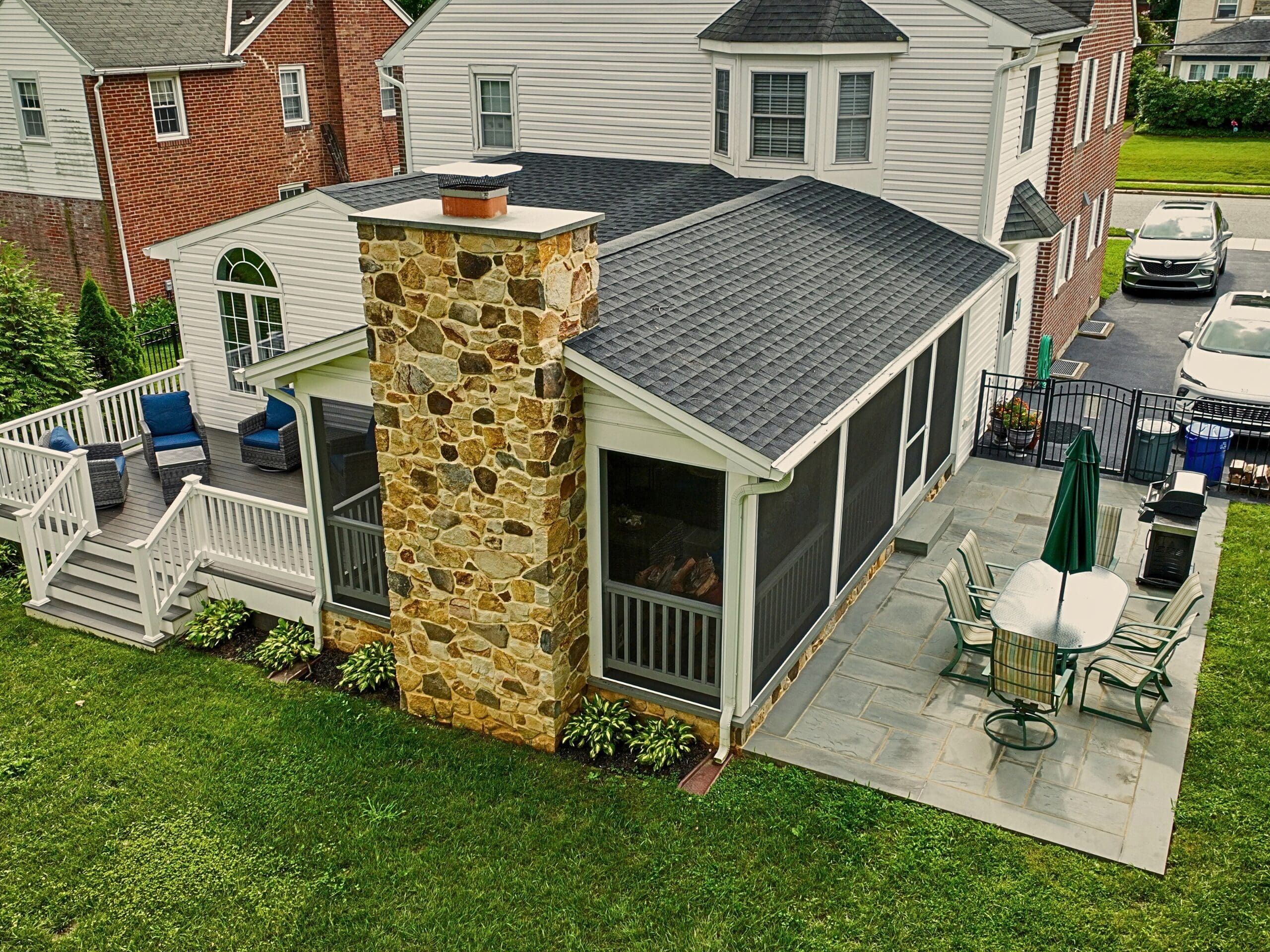 Explore this custom outdoor living transformation featuring an AZEK screened porch, Chester County natural stone fireplace, flagstone patio, and TimberTech composite deck.