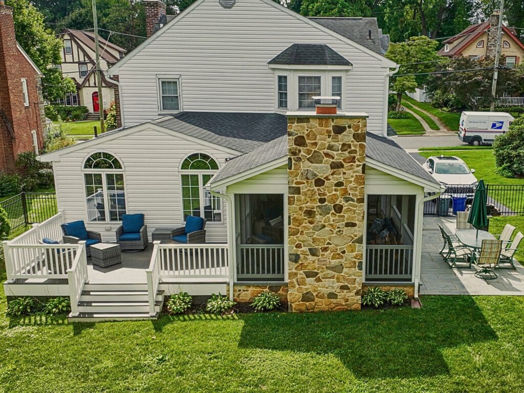 Explore this custom outdoor living transformation featuring an AZEK screened porch, Chester County natural stone fireplace, flagstone patio, and TimberTech composite deck.